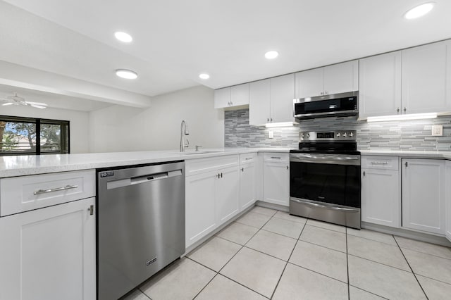 kitchen featuring stainless steel appliances, light tile patterned flooring, white cabinets, and sink