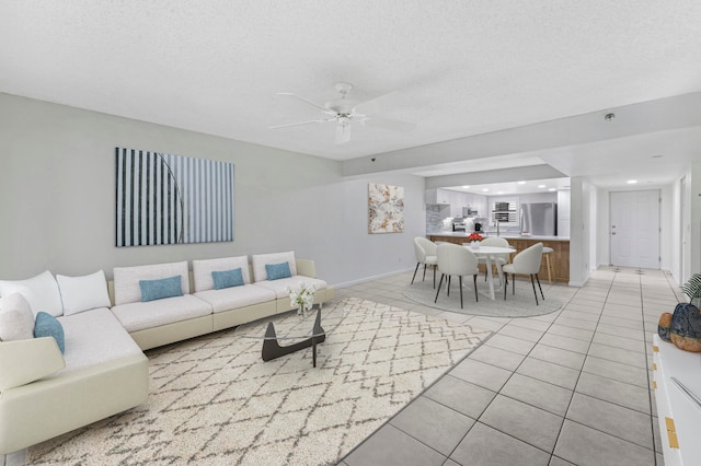 living room featuring a textured ceiling, light tile patterned floors, and ceiling fan