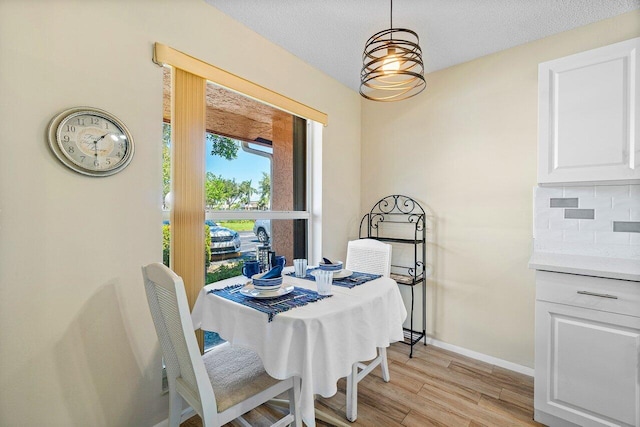 dining space with a textured ceiling and light wood-type flooring