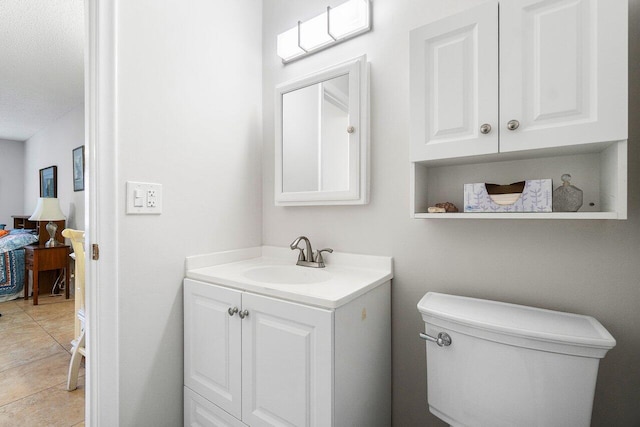 bathroom with a textured ceiling, tile patterned flooring, vanity, and toilet