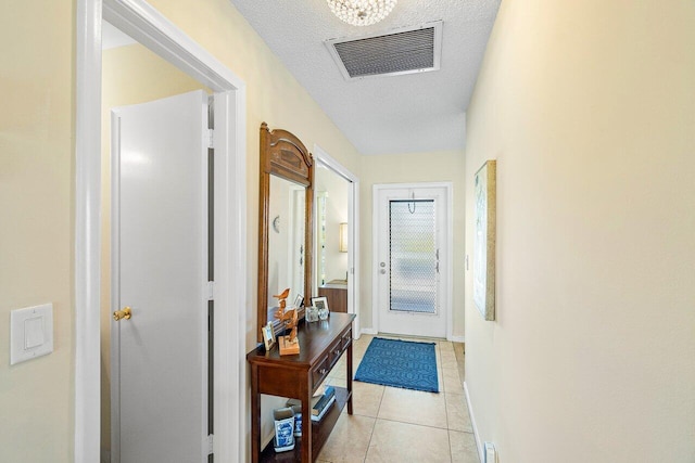 doorway to outside with a textured ceiling and light tile patterned flooring