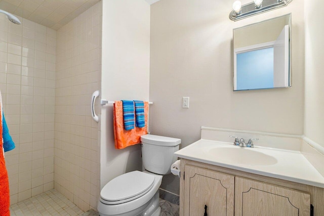 bathroom featuring a tile shower, vanity, and toilet