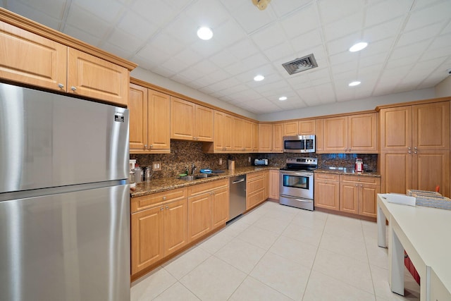 kitchen with stainless steel appliances, light tile patterned floors, tasteful backsplash, and sink