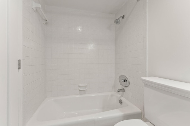 bathroom featuring tiled shower / bath combo and toilet