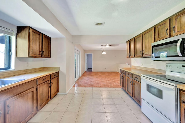 kitchen with sink, light tile patterned flooring, pendant lighting, and electric stove