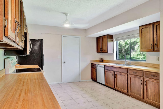 kitchen with sink, dishwasher, light tile patterned flooring, range, and a textured ceiling