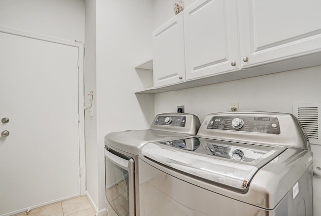 laundry area featuring cabinets, independent washer and dryer, and light tile patterned flooring