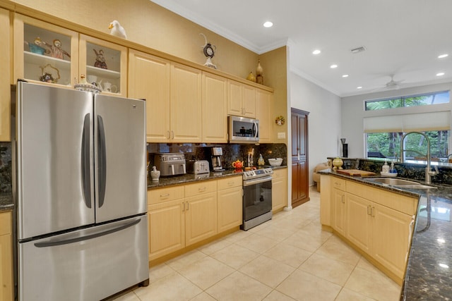 kitchen with sink, ceiling fan, dark stone countertops, appliances with stainless steel finishes, and light tile patterned flooring