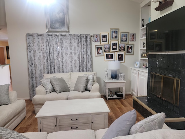 living room featuring built in shelves, hardwood / wood-style flooring, and a fireplace