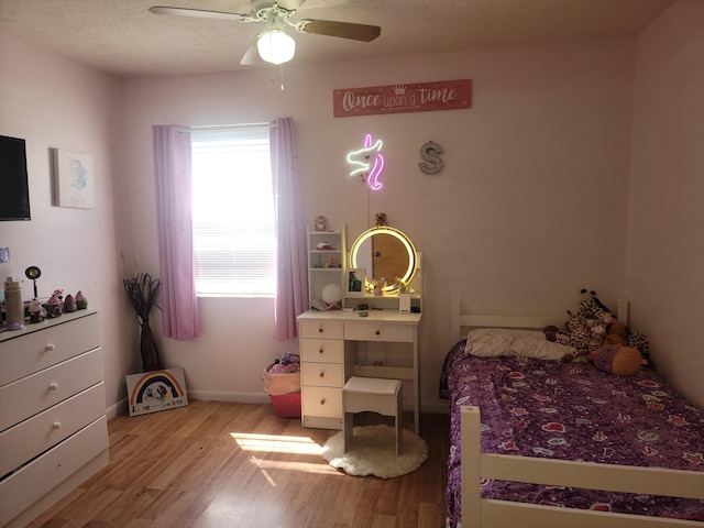 bedroom with light wood-type flooring, ceiling fan, and a textured ceiling