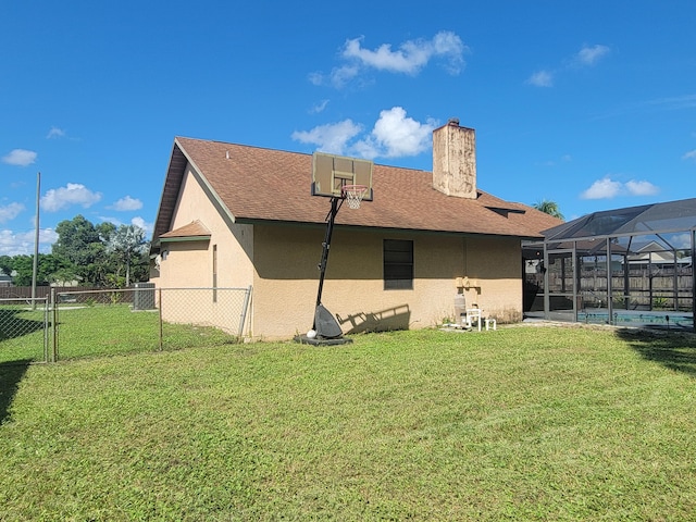 rear view of property with a fenced in pool, a lawn, and a lanai