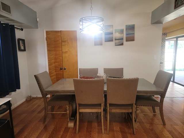 dining area featuring wood-type flooring, an inviting chandelier, and lofted ceiling