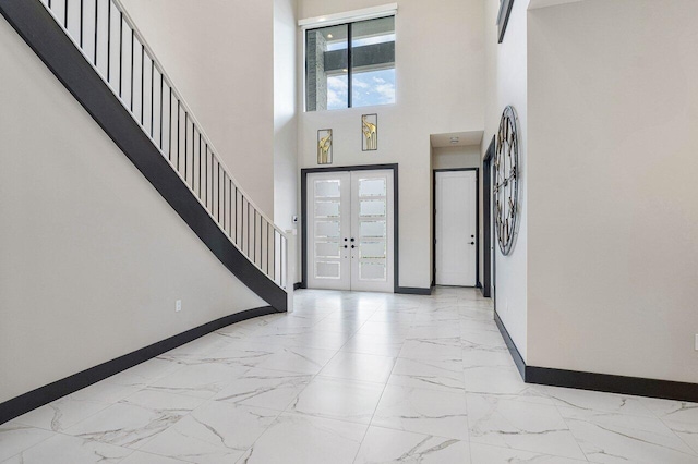 foyer featuring french doors, a towering ceiling, and a wealth of natural light