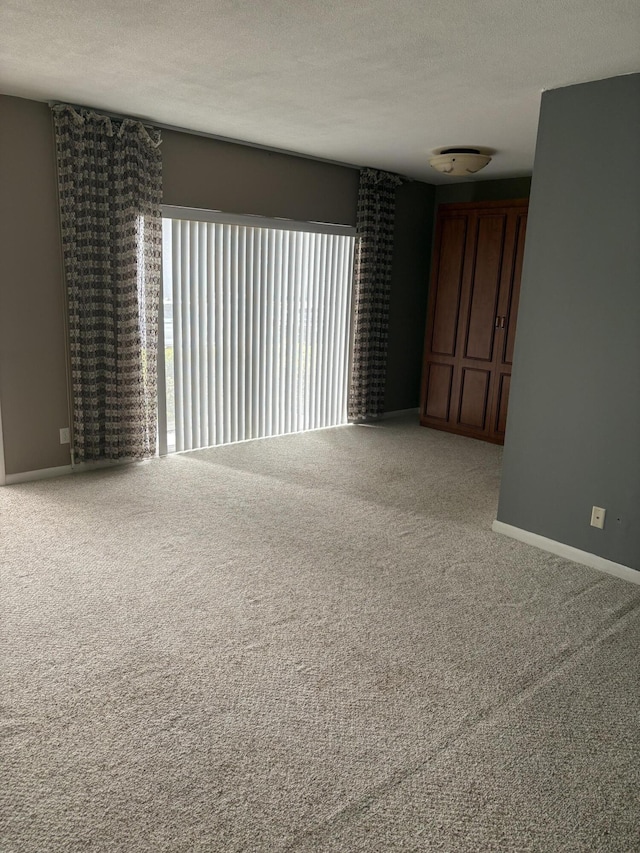 empty room with a textured ceiling and carpet flooring