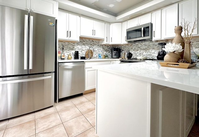 903 9th Ter, Palm Beach Gardens, FL 33418 - kitchen with stainless steel appliances, light tile patterned floors, backsplash, white cabinetry, and light countertops