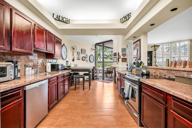 kitchen featuring light stone counters, stainless steel appliances, sink, and a wealth of natural light