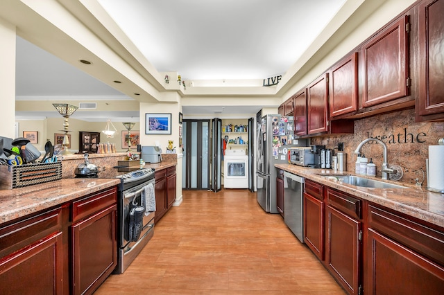 kitchen with stainless steel appliances, tasteful backsplash, sink, ornamental molding, and washer / clothes dryer