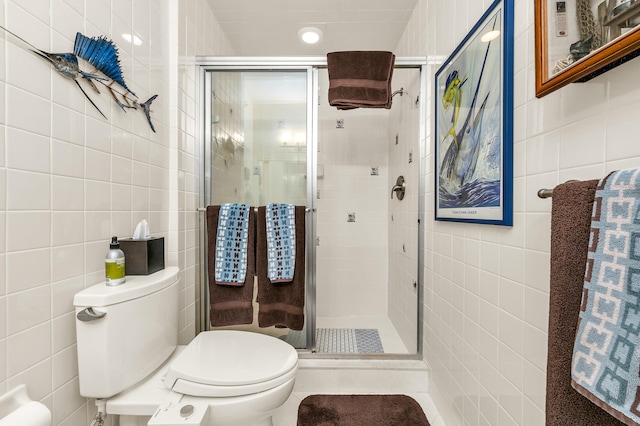 bathroom with tile walls, a shower with door, and toilet