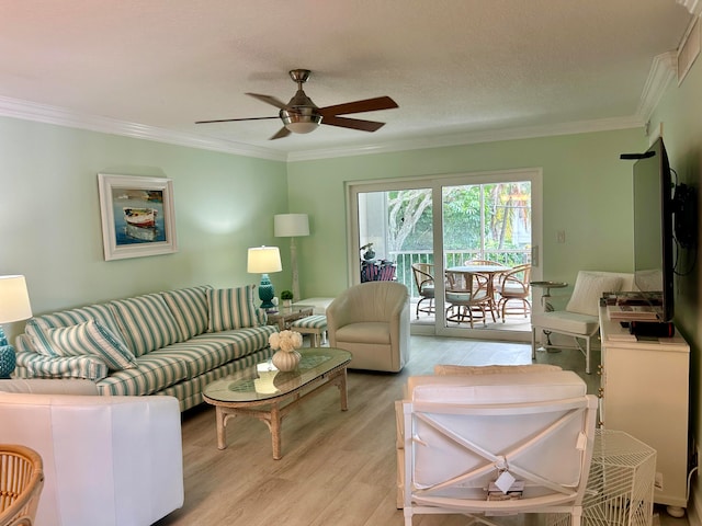 living room featuring light wood-type flooring, a textured ceiling, ceiling fan, and ornamental molding