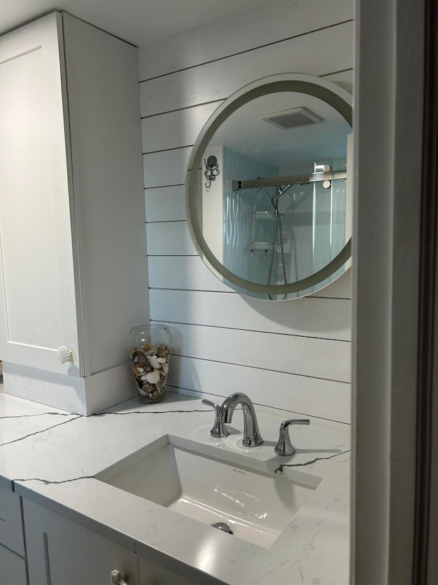 bathroom with wood walls, an enclosed shower, and vanity