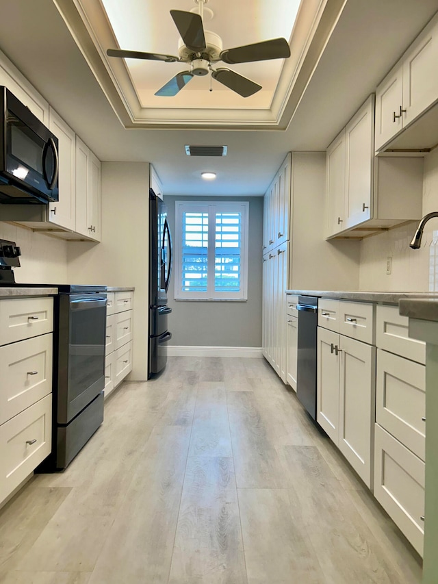 kitchen featuring a tray ceiling, black refrigerator, white cabinets, and stainless steel range with electric stovetop