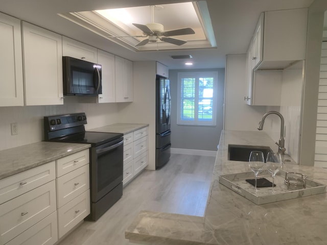 kitchen featuring light hardwood / wood-style floors, white cabinets, a raised ceiling, and stainless steel electric range oven