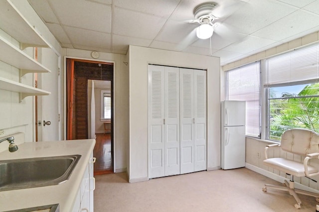 interior space with ceiling fan, light colored carpet, a paneled ceiling, and sink