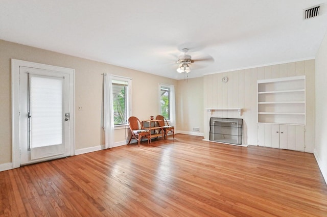 unfurnished living room with ornamental molding, light hardwood / wood-style floors, ceiling fan, and built in features