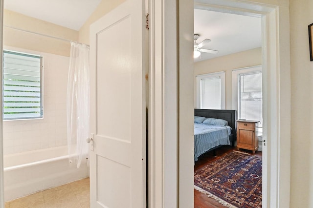 bathroom featuring ceiling fan, hardwood / wood-style flooring, vaulted ceiling, and shower / bath combo