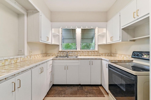 kitchen with white cabinets, tile counters, sink, and range with electric cooktop