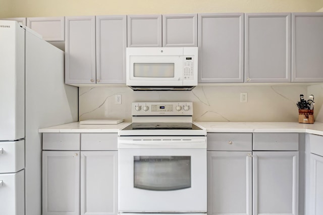 kitchen with light countertops, white appliances, and gray cabinetry