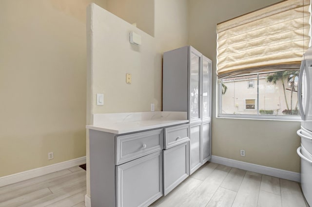 kitchen featuring light stone countertops, light wood finished floors, and baseboards