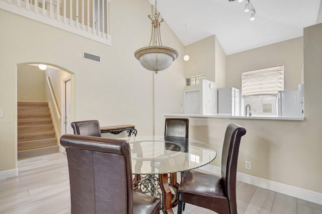 dining room featuring arched walkways, stairway, wood finished floors, and baseboards