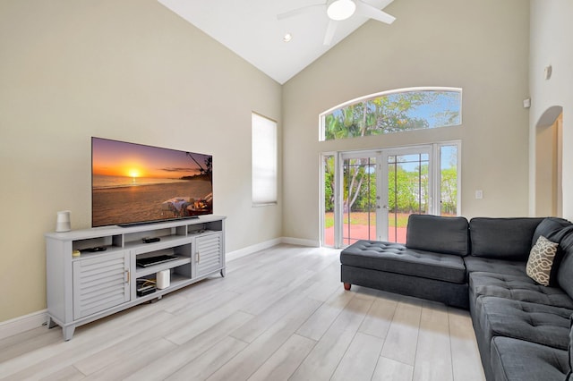 living room featuring french doors, ceiling fan, high vaulted ceiling, light wood-type flooring, and baseboards