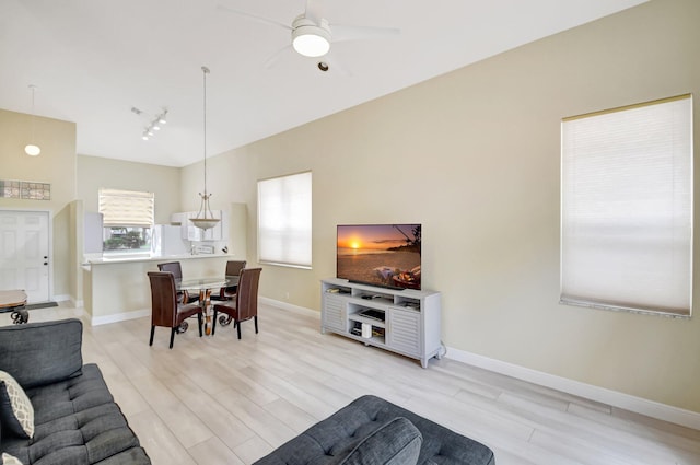 living room with ceiling fan, track lighting, light wood-type flooring, and baseboards