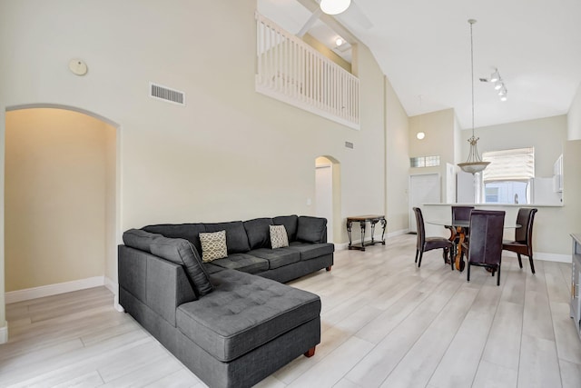 living room with arched walkways, visible vents, light wood-style flooring, and baseboards