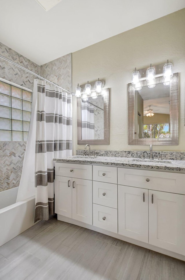 bathroom with double vanity, shower / bath combination with curtain, ceiling fan, and a sink