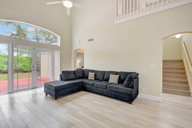 living room featuring arched walkways, wood finished floors, visible vents, baseboards, and stairs