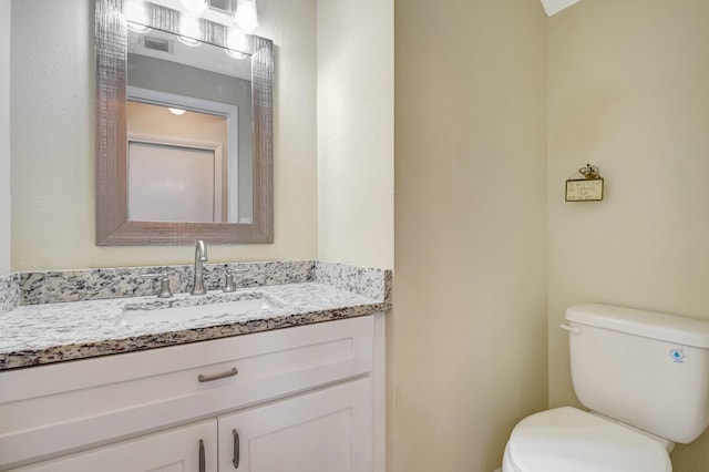 half bathroom featuring visible vents, vanity, and toilet