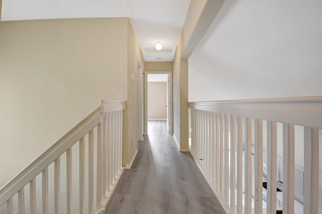 corridor featuring baseboards, wood finished floors, and an upstairs landing