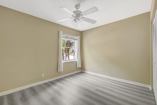 unfurnished room with ceiling fan, a textured ceiling, baseboards, and wood finished floors