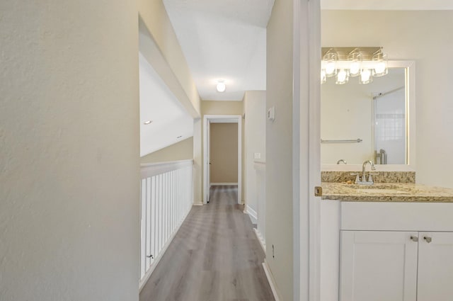 hallway featuring light wood finished floors, a sink, and baseboards