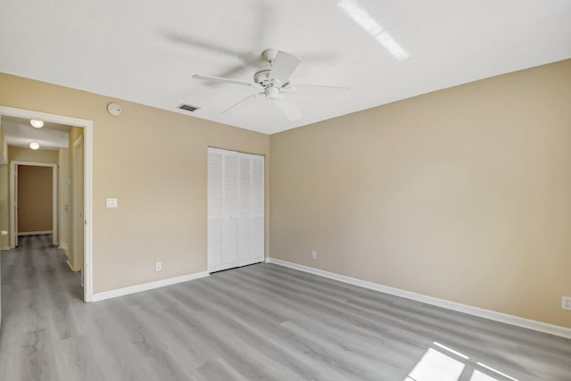 unfurnished bedroom featuring baseboards, visible vents, ceiling fan, light wood-type flooring, and a closet