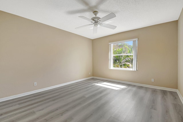 unfurnished room featuring a textured ceiling, ceiling fan, wood finished floors, and baseboards