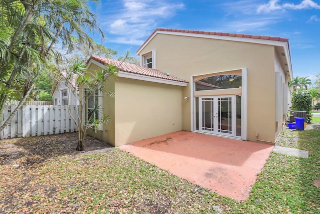 rear view of property with a patio, central AC unit, fence, french doors, and stucco siding