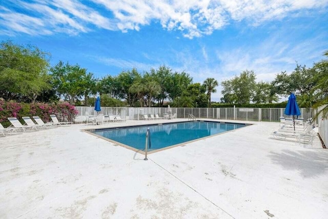 pool with a patio area and fence