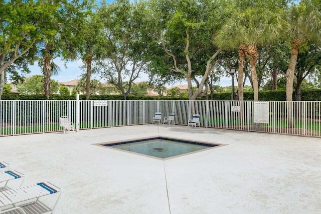 view of swimming pool with fence, a community hot tub, and a patio