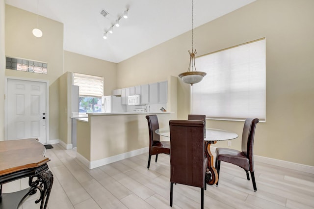 dining space featuring light wood-type flooring, baseboards, visible vents, and track lighting