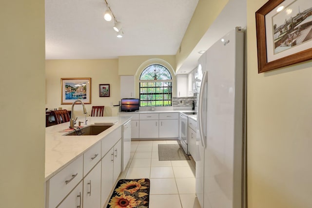 kitchen with white cabinetry, sink, light stone countertops, white appliances, and light tile patterned floors