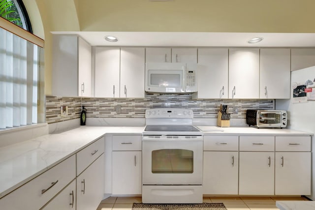 kitchen featuring white cabinets, light tile patterned floors, white appliances, and backsplash